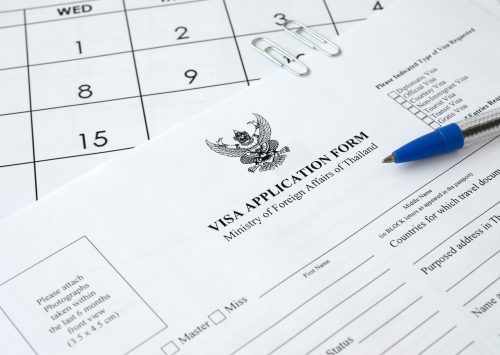 Thailand Visa application form and blue pen on paper calendar page close up